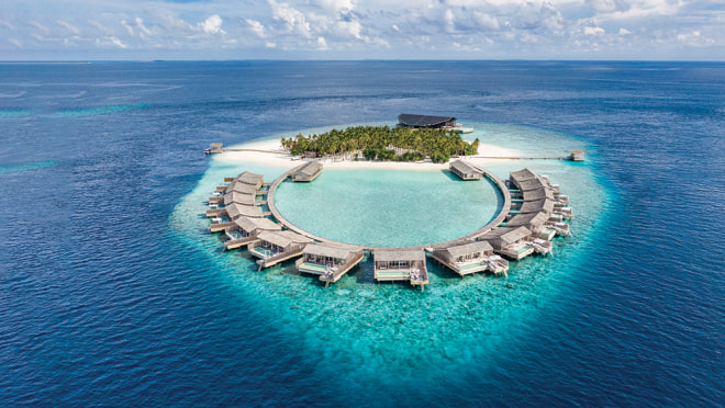 Aerial view of a sustainable luxury resort with over water villas and views of the Indian ocean