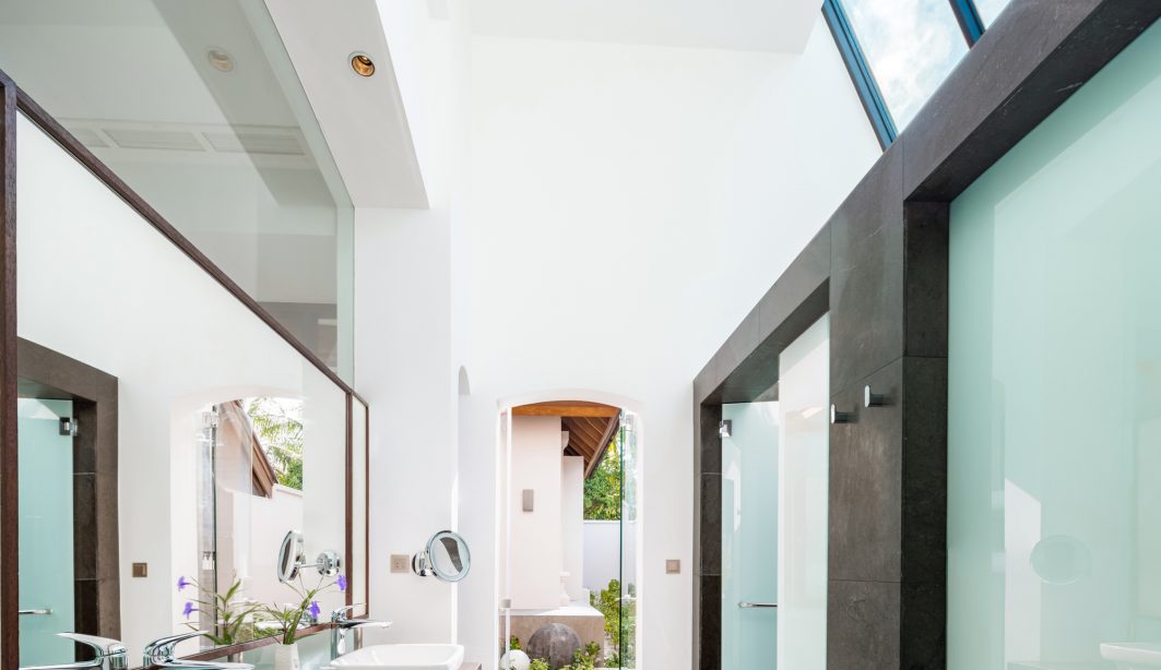 Bright modern bathroom design with long mirror and angled skylights