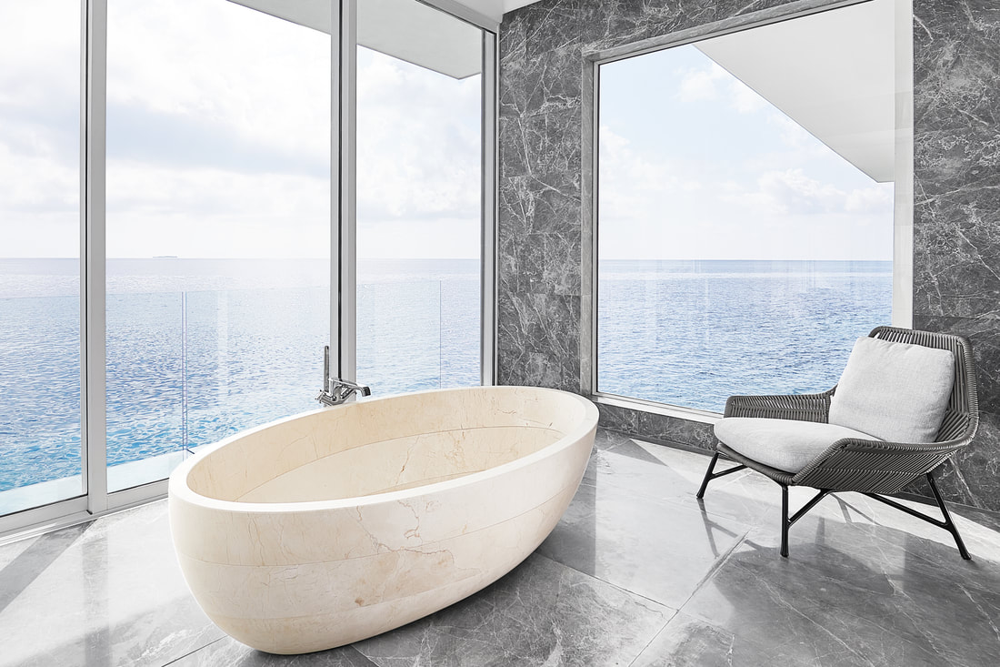 A view of the unobstructed Maldivian ocean from the modern bathroom of the over water villa. Relax in the white marble tub and watch the tranquil waves during your opulent get-away.