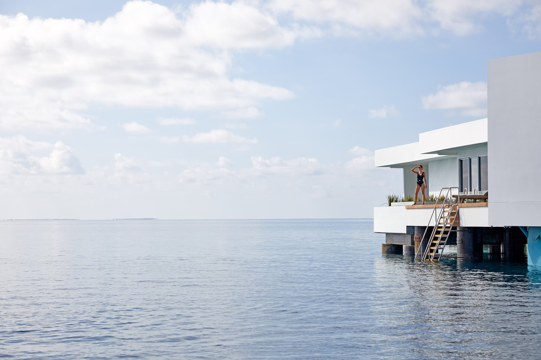 Side view of the luxury over water villa with a guest looking out to the ocean