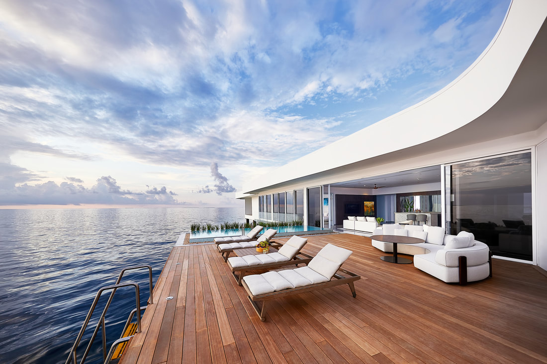 Looking out to the ocean horizon from the floating wooden deck of the over-water villa suite. At the edge of the deck is an infinity pool. The villa has expansive sliding doors for a blurred boundary between exterior and interior.