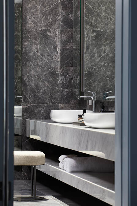 Luxury bathroom vanity with white marble supporting bowl sinks and a modern black marble finish for the walls.