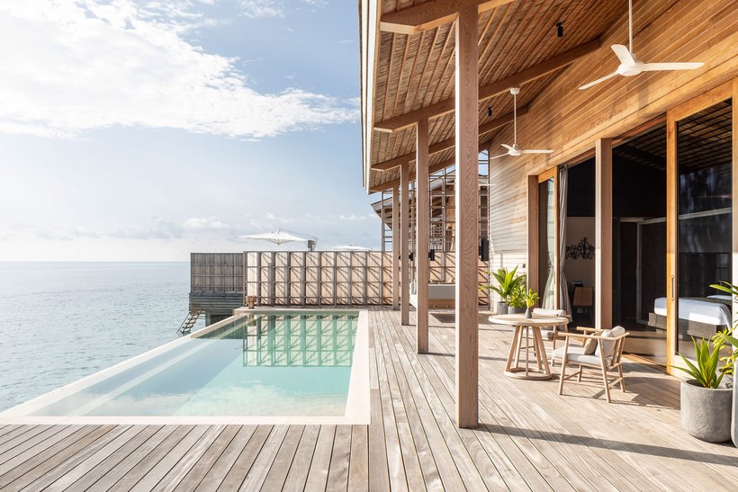 On the deck of an over water luxury high end villa, there's an infinity pool and beautiful ocean horizon